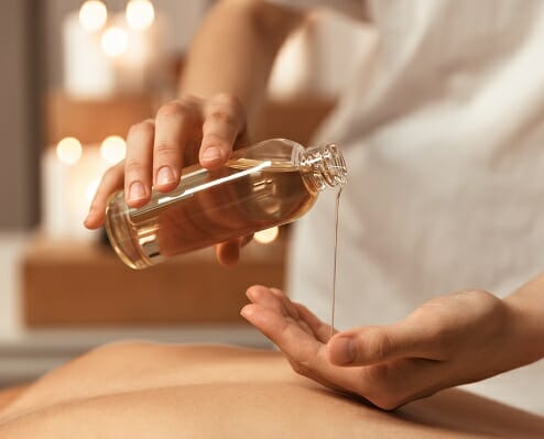 Close up of a woman masseur pouring massage oil