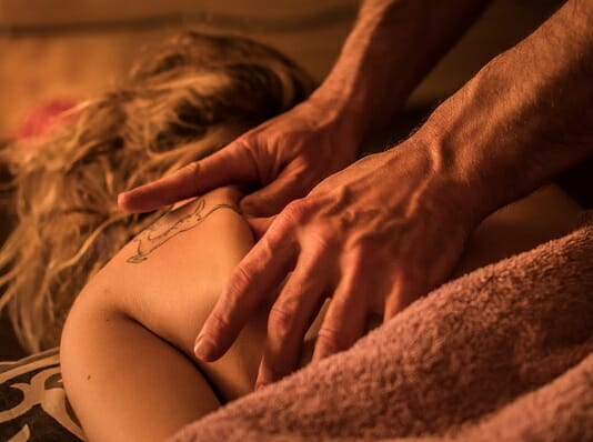 Strong hands do a massage on the warm light, strongly presses, young woman body